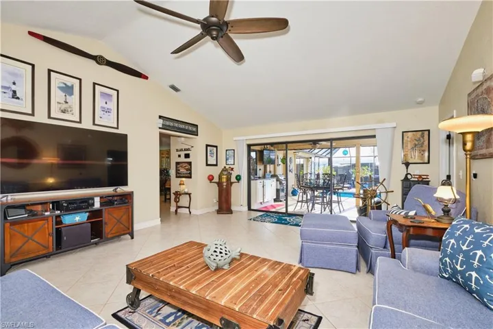 Living area featuring light tile patterned flooring, high vaulted ceiling, a ceiling fan, baseboards, and visible vents