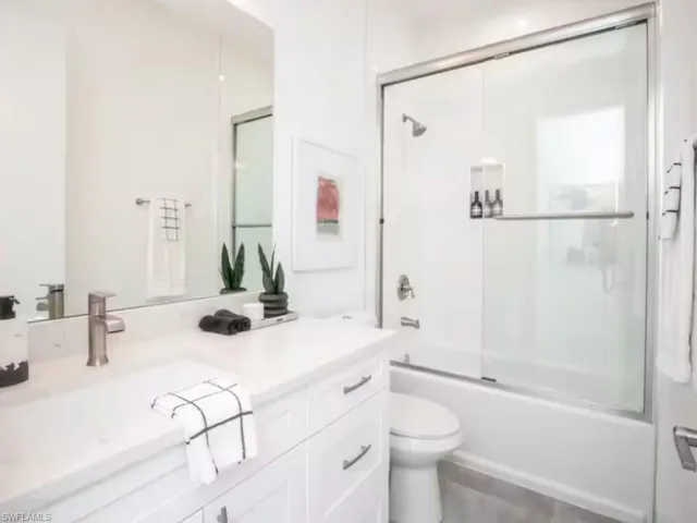Bathroom featuring a white vanity with a single sink, brushed nickel faucet, and white countertop