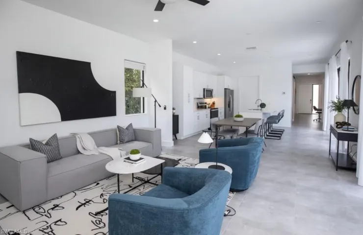 Open-concept living space featuring light gray tile flooring, a contemporary ceiling fan, recessed lighting, and a kitchen with white cabinetry and stainless steel appliances