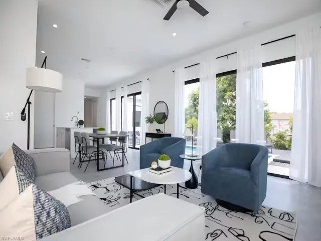 Open-concept living space featuring high ceilings, recessed lighting, and expansive floor-to-ceiling windows with sliding glass door access to the pool