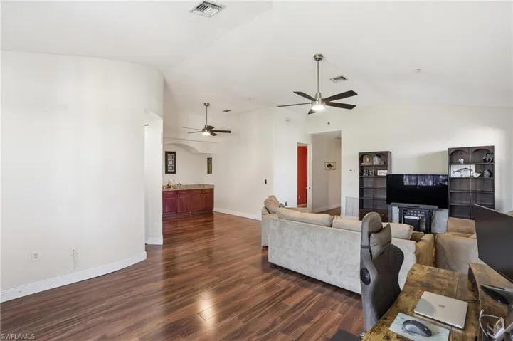 Living area with dark wood finished floors, ceiling fan, and a high ceiling