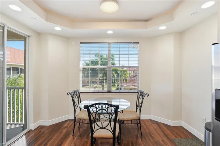 Dining area featuring plenty of natural light, dark wood finished floors, recessed lighting, and a raised ceiling
