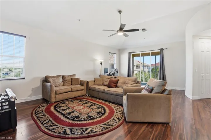 Living room with dark wood-type flooring, lofted ceiling, and ceiling fan