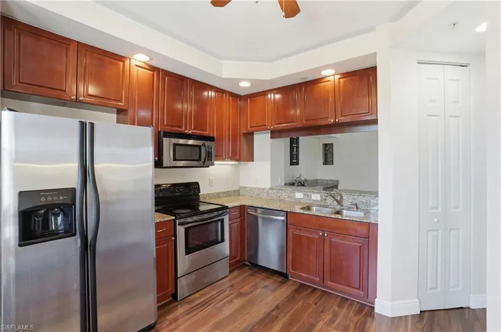 Kitchen featuring stainless steel appliances, a ceiling fan, dark wood-style flooring, light stone countertops, and recessed lighting