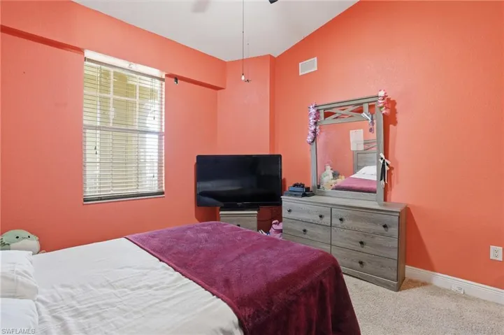 Bedroom featuring carpet flooring, lofted ceiling, a textured wall, and ceiling fan