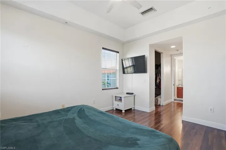 Bedroom featuring a spacious closet, dark wood-style floors, ceiling fan, and ensuite bathroom