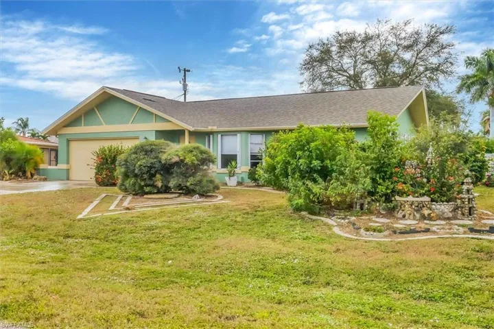 Ranch-style house with a front yard, a garage, and driveway