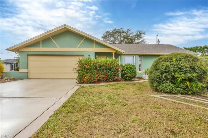 Single story home with an attached garage, driveway, a front lawn, stucco siding, and brick siding