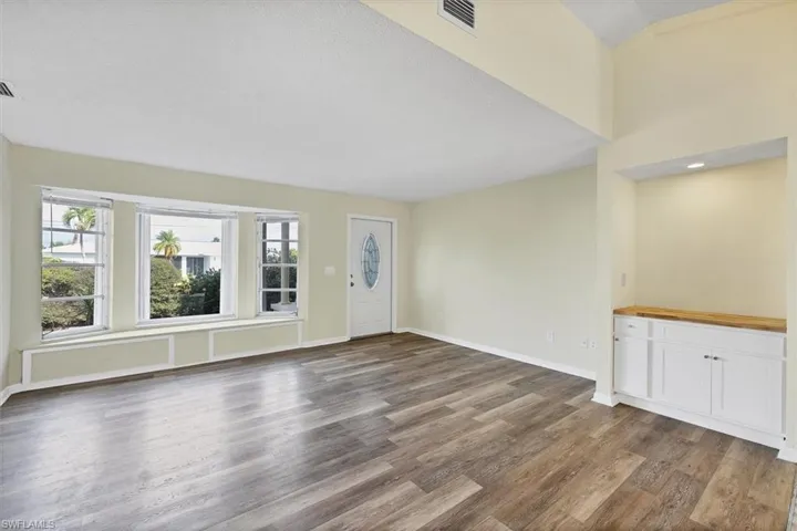 Unfurnished living room featuring a textured ceiling and dark wood-style flooring