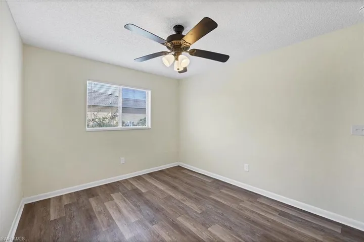 Empty room with a textured ceiling and dark wood-style flooring