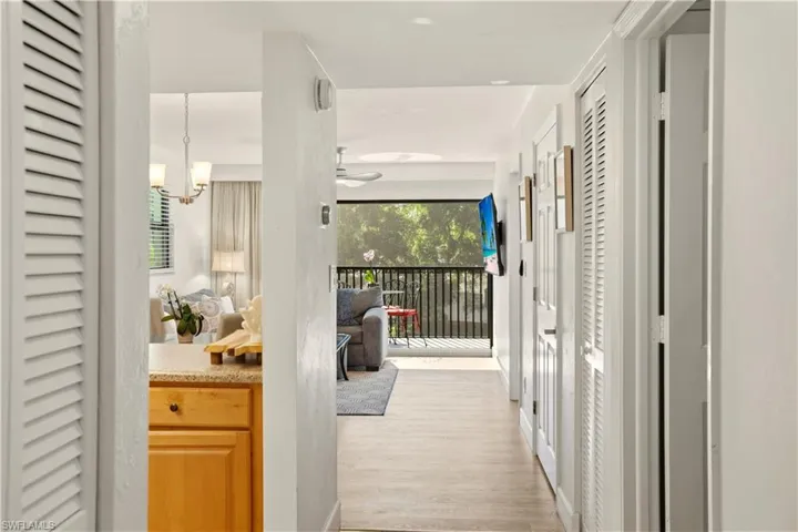 Hallway featuring light wood-style flooring, plenty of natural light, and hanging lights