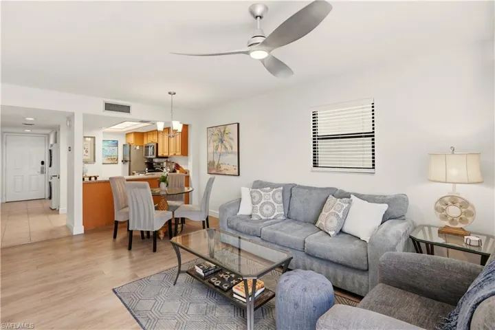 Living area featuring light wood-style flooring, ceiling fan, and suspended lighting