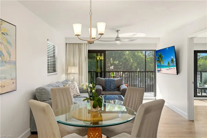 Dining room featuring ceiling fan, wood finished floors, a chandelier, and plenty of natural light