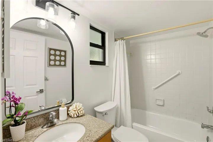 Bathroom featuring vanity and shower / bathtub combination with curtain