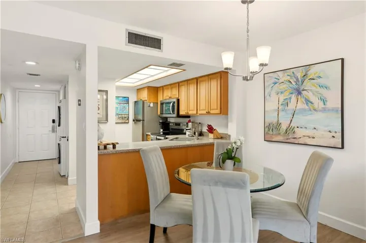Kitchen with stainless steel appliances, a peninsula, light wood-style floors, wood finish cabinets, and a chandelier