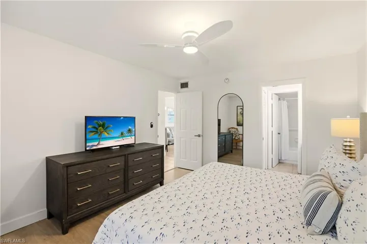 Bedroom with a ceiling fan, light wood-style floors, and ensuite bathroom