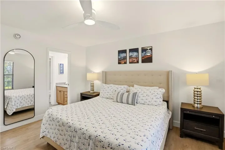 Bedroom featuring ensuite bathroom, light wood-style floors, and ceiling fan
