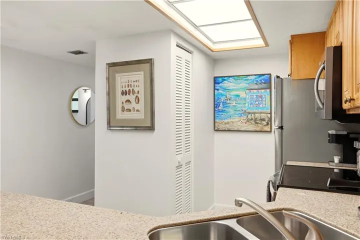 Kitchen featuring light stone countertops, range with electric stovetop, stainless steel microwave, and a skylight