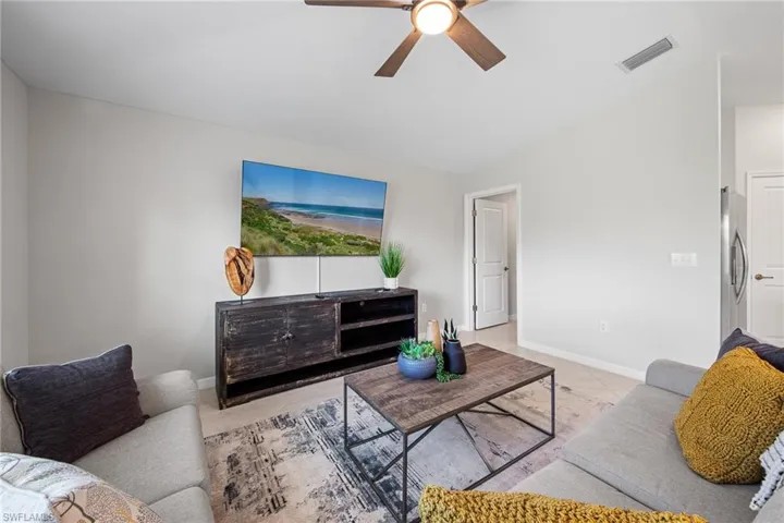 Living room featuring ceiling fan, light tile patterned floors, and vaulted ceiling
