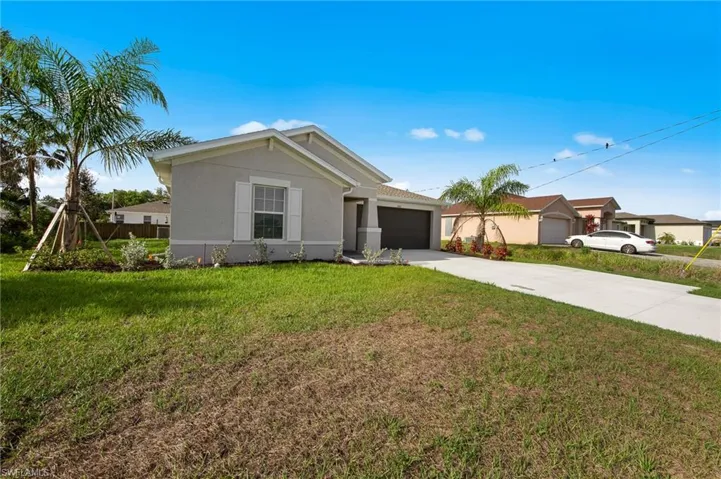 Single story home featuring stucco siding, driveway, an attached garage, and a front lawn