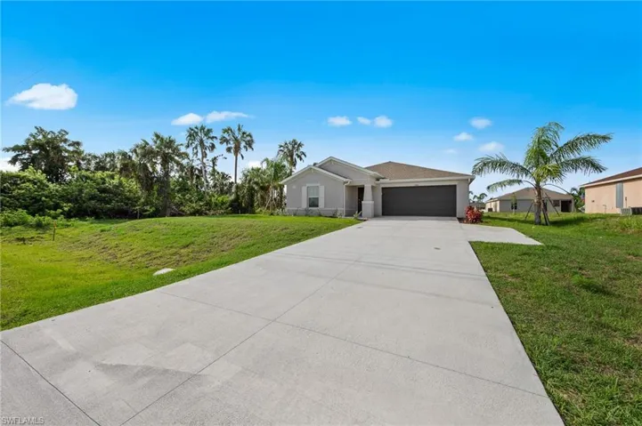 Ranch-style house featuring concrete driveway, a garage, a front lawn, and stucco siding