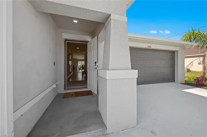 View of exterior entry with stucco siding and a garage