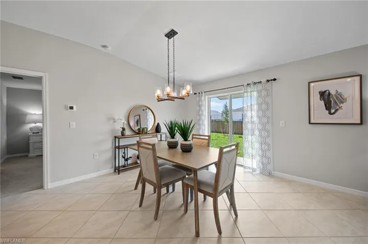 Dining area featuring a chandelier, vaulted ceiling, and light tile patterned flooring