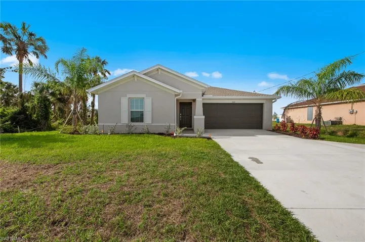 Ranch-style home featuring stucco siding, a garage, driveway, and a front yard