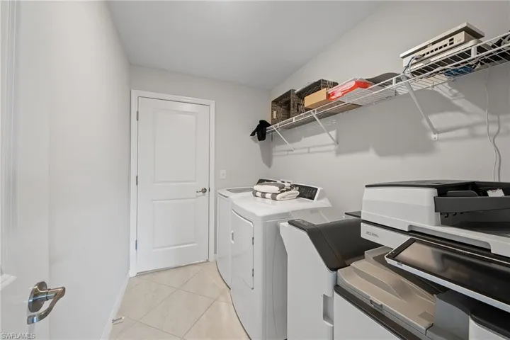 Washroom with independent washer and dryer and light tile patterned floors