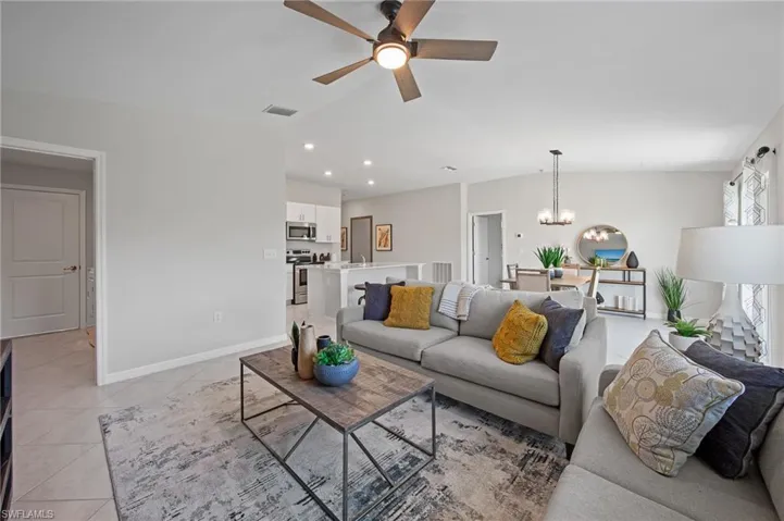 Living area featuring a chandelier, ceiling fan, light tile patterned floors, lofted ceiling, and recessed lighting