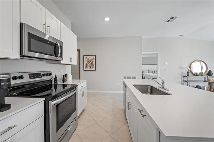 Kitchen with stainless steel appliances, light countertops, light tile patterned floors, white cabinets, and recessed lighting