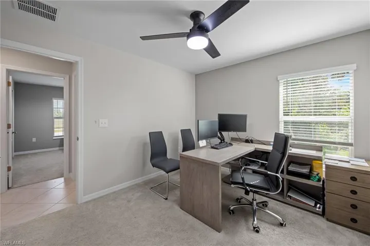 Office area with light carpet, a ceiling fan, and light tile patterned floors