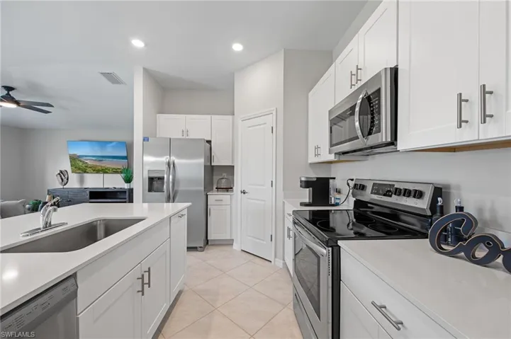 Kitchen with appliances with stainless steel finishes, light countertops, white cabinets, recessed lighting, and open floor plan