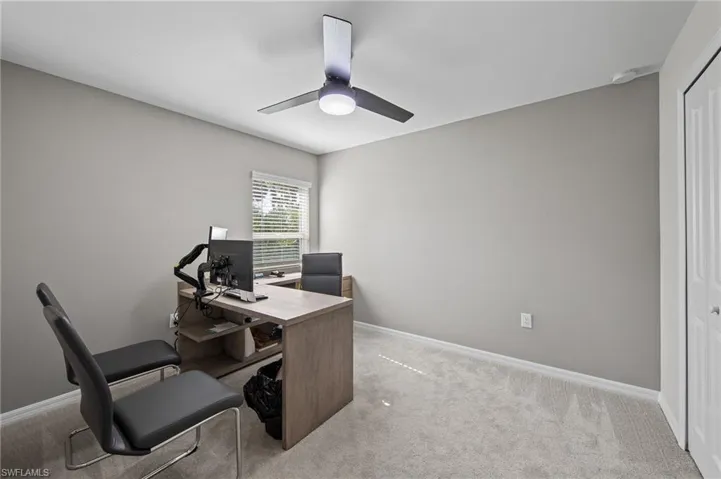 Home office with ceiling fan and light colored carpet