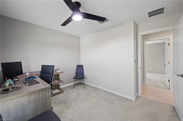 Office space featuring light carpet, ceiling fan, and light tile patterned flooring