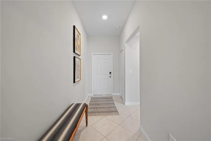 Hallway with light tile patterned floors and recessed lighting