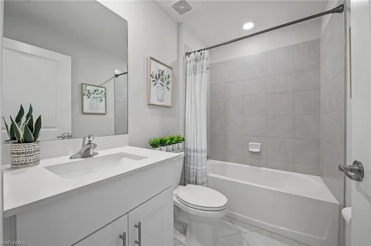 Full bath with vanity, shower / bath combo, and tile patterned flooring