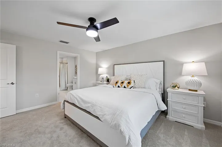 Carpeted bedroom with ensuite bath and a ceiling fan
