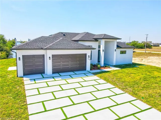 View of front of property featuring , an attached 3 car garage, custom driveway, and a front yard