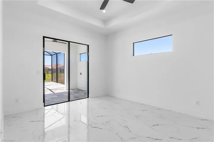 Bright and Airy Primary w a viewturing baseboards, marble finish floor, ceiling fan, and a raised ceiling