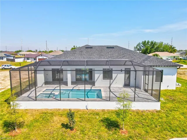 View of pool with a pool with connected hot tub, a lawn, glass enclosure, and a patio