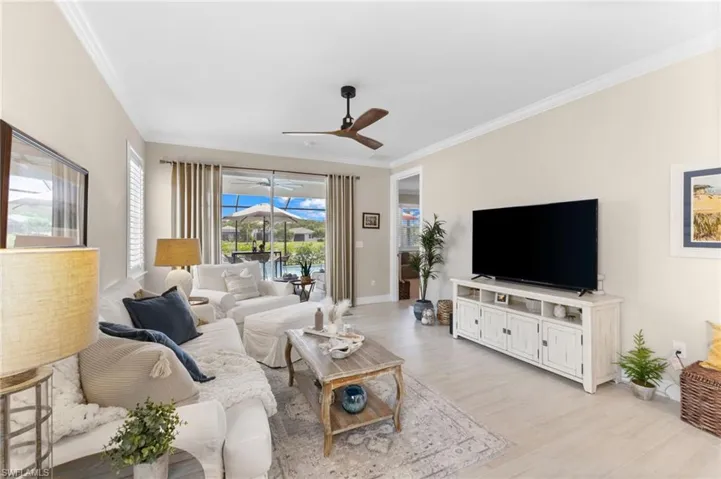 Living room with light hardwood / wood-style floors, ceiling fan, and ornamental molding