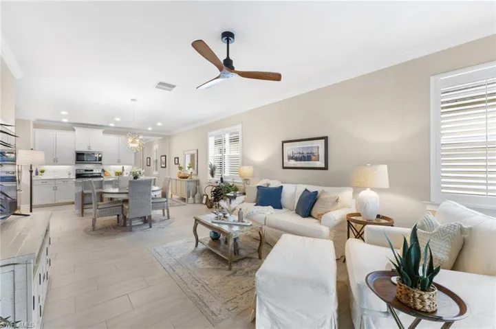 Living room with ceiling fan with notable chandelier and crown molding