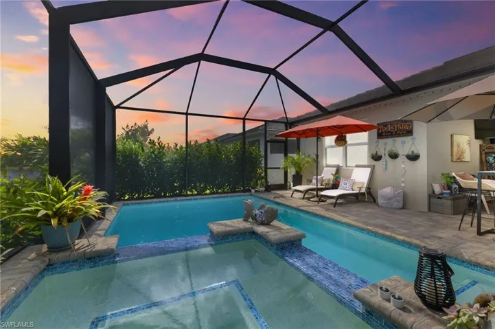 Pool at dusk with a patio and glass enclosure