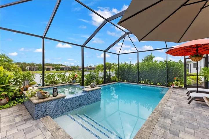 View of pool featuring a patio area, an in ground hot tub, and glass enclosure