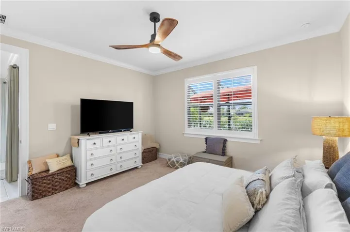 Carpeted bedroom with ornamental molding and ceiling fan