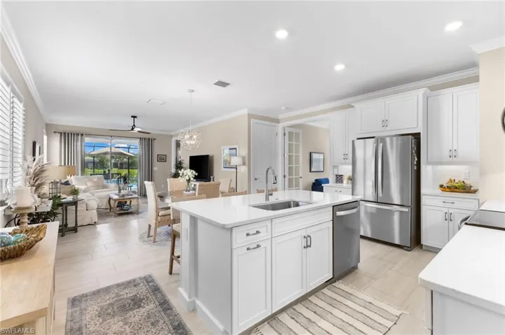Kitchen with white cabinetry, ceiling fan, stainless steel appliances, sink, and a center island with sink