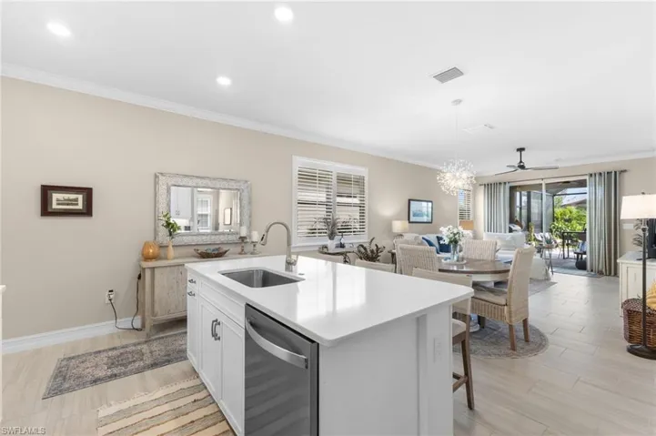 Kitchen with dishwasher, ceiling fan with notable chandelier, a kitchen island with sink, hanging light fixtures, and sink