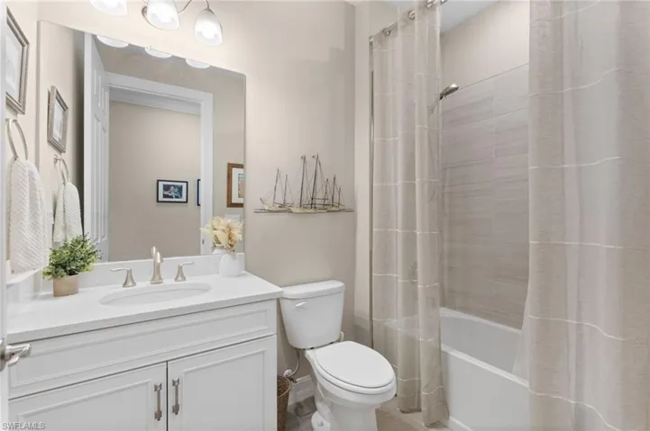 Full bathroom with vanity, shower / bathtub combination with curtain, and toilet