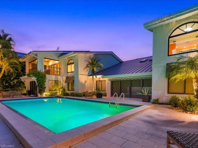 Pool at dusk featuring a patio, an outdoor pool, and a balcony